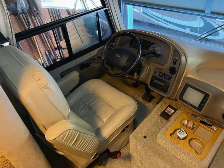 Explore this RV rental's inviting cockpit! Tan leather driver's seat, Ford steering wheel, and a spacious dashboard ready for adventure.. National RV Sea Breeze 2006