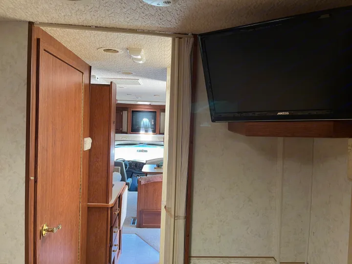 Step inside this cozy RV rental, featuring a living area with TV and a view into the cabin. Perfect for road trips.. Itasca Sundancer 2001