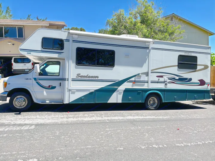 Side profile of a white and teal Itasca Sundanceer RV rental parked on a sunny day.. Itasca Sundancer 2001