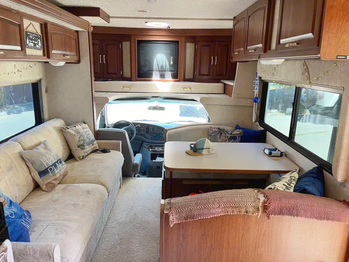 Spacious RV rental interior: visible are a comfortable sofa, dining area, and the front cockpit, creating a cozy mobile living space.. Itasca Sundancer 2001