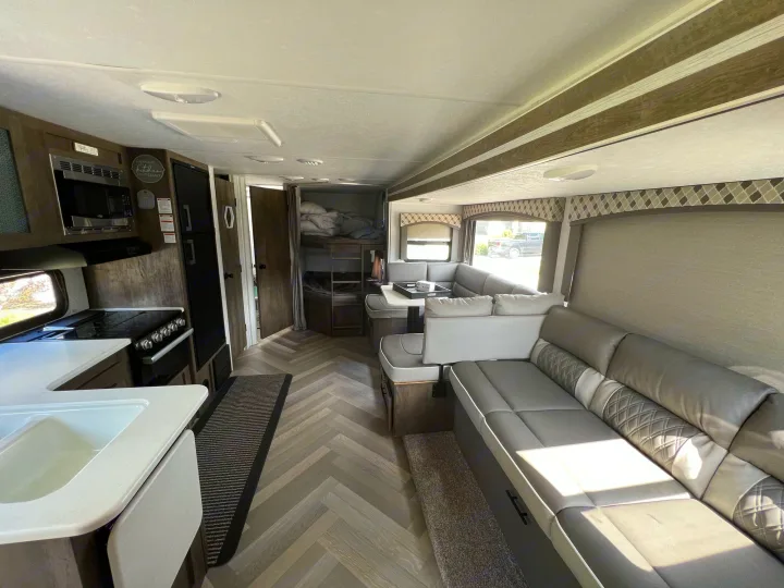 Explore this well-appointed rv rental interior with kitchen, dinette, sofa, and bunk beds. Stylish herringbone floor.. Forest River EVO 2700 BHX 2022