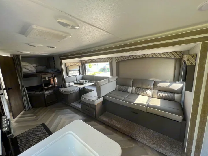 Spacious RV rental interior featuring a large gray U-shaped dinette, bunk beds, and modern herringbone flooring.. Forest River EVO 2700 BHX 2022