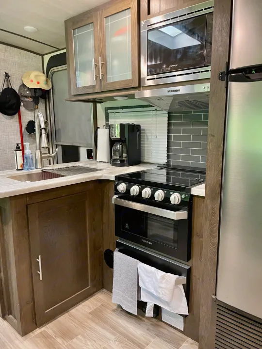 Experience comfortable cooking in this RV rental kitchen, equipped with a sink, Furrion microwave, stove, and refrigerator.. Forest River Salem Hemisphere 2020