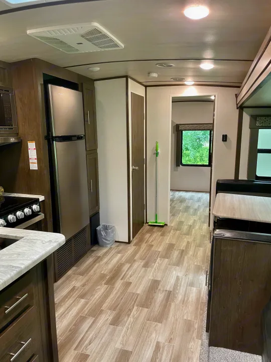 Clean, bright RV rental interior featuring a kitchen, dinette, and wide hallway with wood-look floors.. Forest River Salem Hemisphere 2020