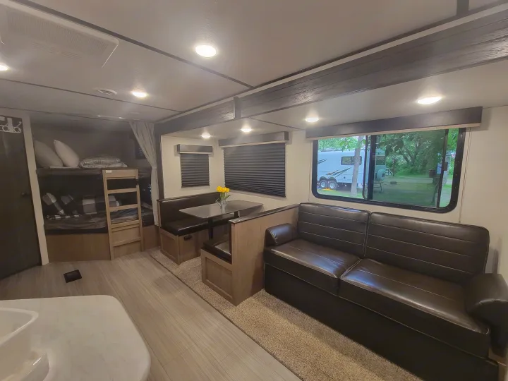 Spacious RV rental interior featuring bunk beds, a dinette, and a comfortable sofa, perfect for families.. Keystone RV Hideout 2021