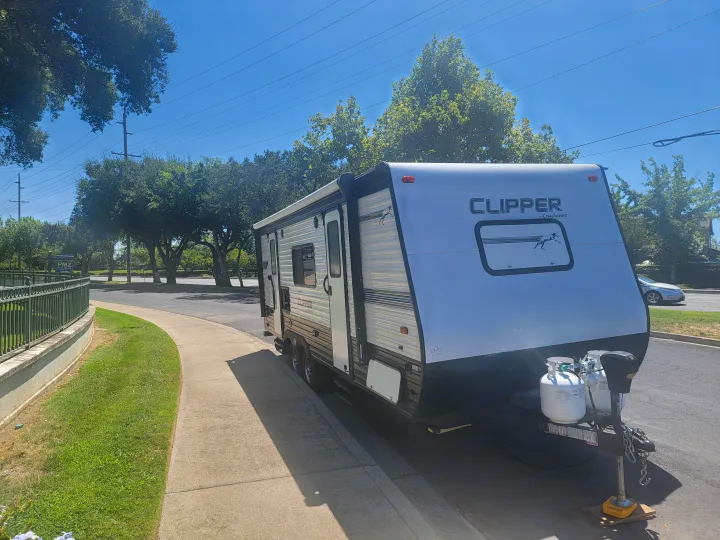 Front view of a white Coachmen Clipper travel trailer, with propane tanks, ready for RV rental.. Clipper Clipper Trailer 2019
