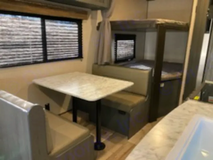 RV rental interior: A dinette with bench seating is on the left; bunk beds are visible in the background, offering compact comfort.. Dutchmen Other 2022