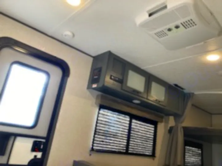 Inside a modern RV rental: Overhead cabinets, AC, and a window with blinds offer comfort for your next adventure.. Dutchmen Other 2022