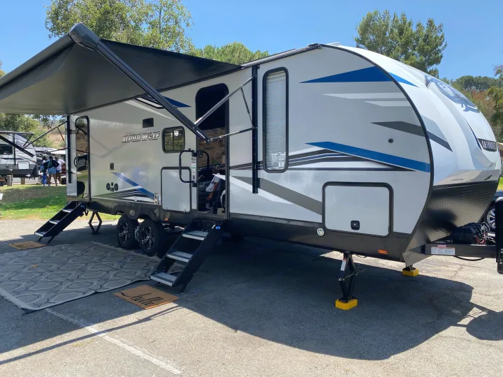 Spacious Alpha Wolf RV rental, featuring an extended awning, steps, and outdoor setup for a sunny adventure.. Forest River Cherokee 2022