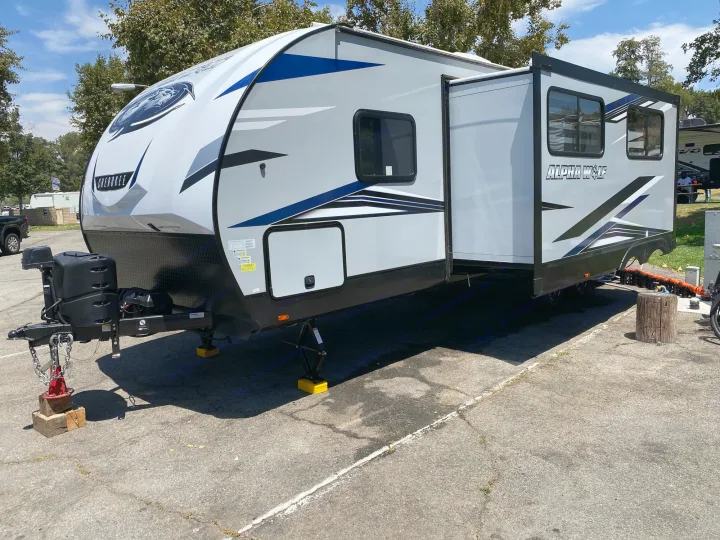 Spacious grey & blue Alpha Wolf Cherokee travel trailer, an ideal rv rental setup, parked on asphalt for your outdoor adventure.. Forest River Cherokee 2022