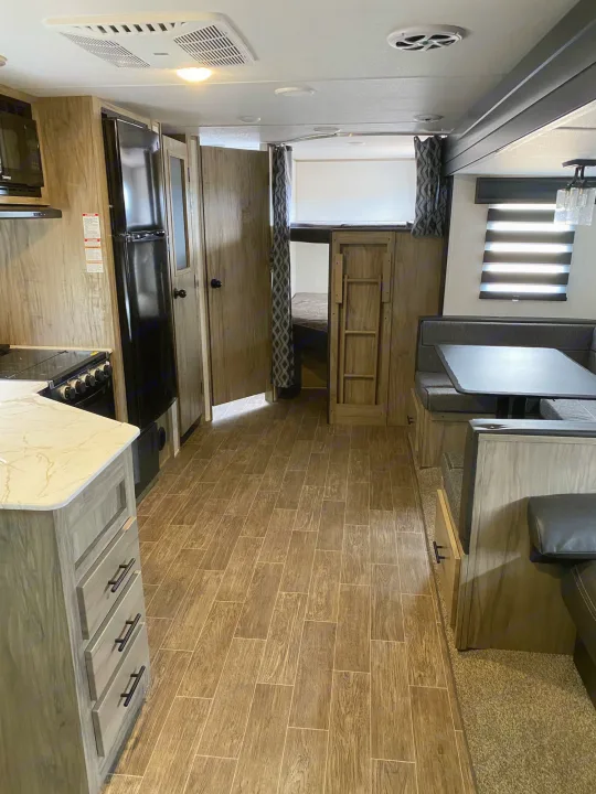 RV rental interior showcasing a kitchen, dinette, and bunk beds. Features wood-look flooring and ceiling AC.. Forest River Cherokee 2022