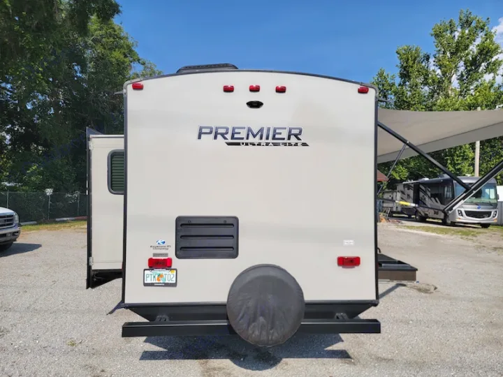 Rear view of a Premier Ultra-Lite travel trailer, an excellent RV rental option. Note the rear-mounted spare tire.. Keystone RV Premier UltraLite 29RKPR 2021