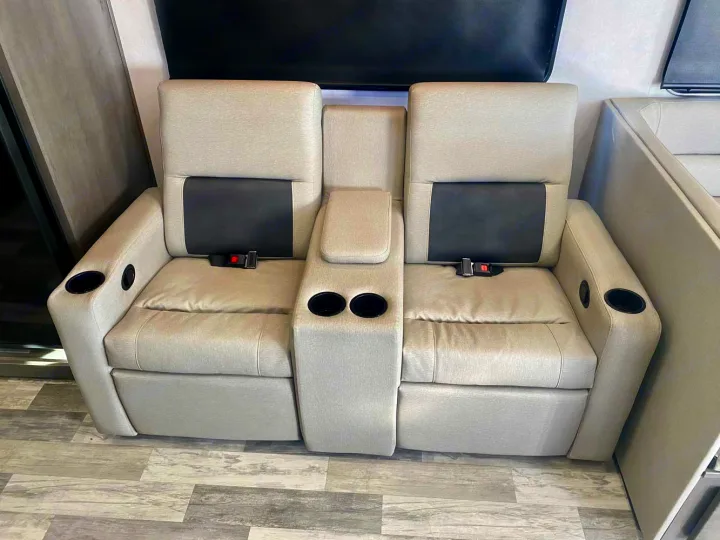 Relax in this RV rental's theater seating: two beige recliners with black accents, multiple cup holders, and seatbelts.. Forest River FR3 34DL 2020