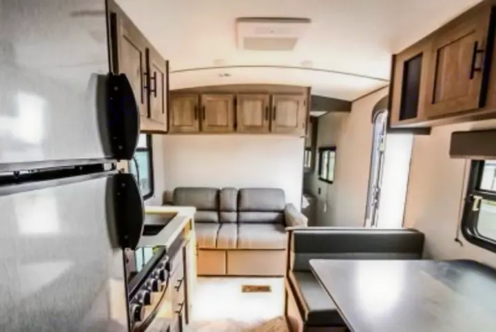 Spacious RV rental interior featuring a modern kitchen with fridge, a cozy sofa, and a dining booth. Ideal travel camper.. Keystone RV Springdale 2021