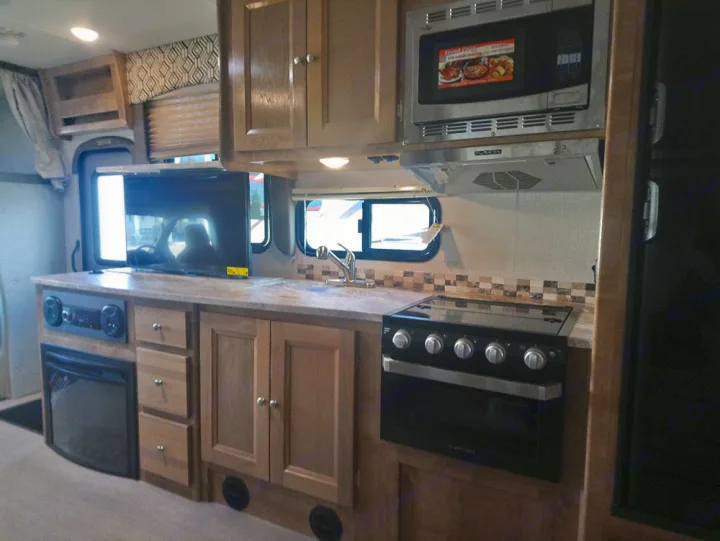 An RV rental interior featuring a full kitchen with microwave, stove, sink, plus an entertainment system with TV and fireplace.. Forest River Coachmen Leprechaun 2019