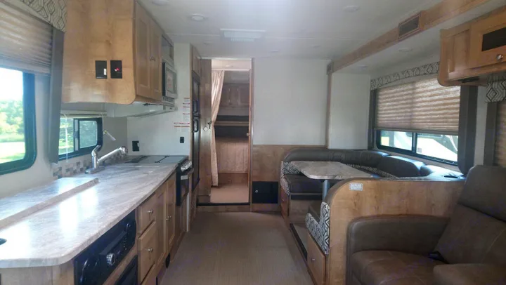 Modern RV rental interior: well-equipped kitchen, U-shaped dinette, lounge, and private bunk area.. Forest River Coachmen Leprechaun 2019