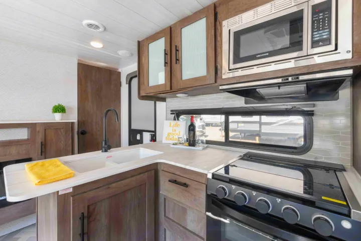 Modern RV rental kitchen featuring a sink, microwave, and stove. Compact design for comfortable travel cooking.. Forest River Salem Cruise Lite 2022
