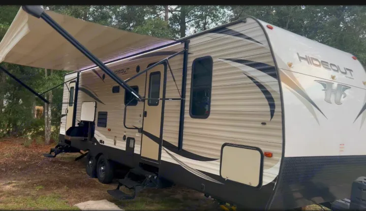 This Hideout RV rental is set up with its awning extended and steps down, ready for an outdoor camping adventure.. Keystone RV Hideout 2018