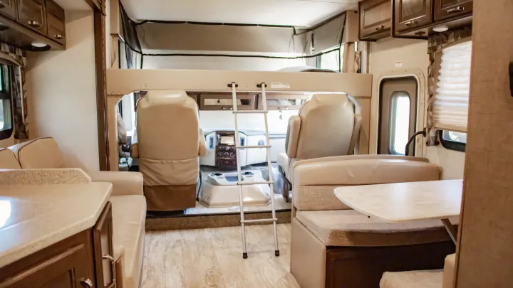 Spacious RV rental interior showcasing an overhead bunk, dinette, and kitchen area. Perfect for family adventures.. Thor Hurricane 2017