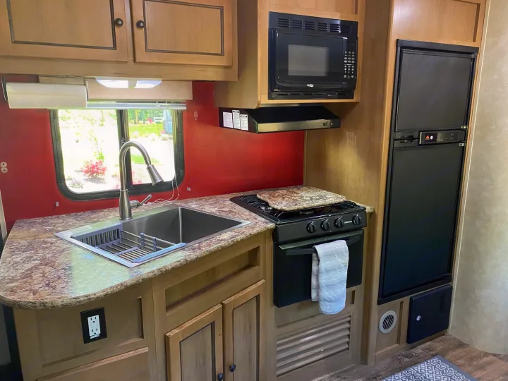 Step inside this RV rental's well-equipped kitchen, featuring a sink, stove, microwave, and refrigerator.. Cruiser Rv Corp 280Bunkhouse Cruiser 2015