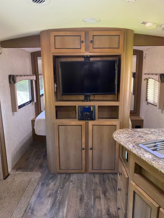 Inside this RV rental: a central TV/stereo console, kitchen counter, and a bedroom beyond. Enjoy your mobile living space.. Cruiser Rv Corp 280Bunkhouse Cruiser 2015