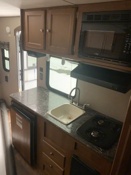 Compact RV rental kitchen features a sink, stovetop, microwave, fridge, and ample cabinets for comfortable travel.. Springdale Summit 2017