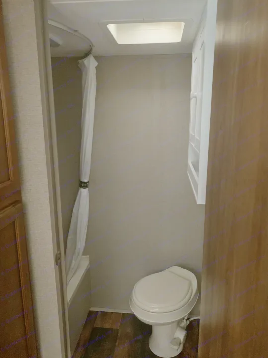 Compact RV rental bathroom featuring a toilet, shower with curtain, and overhead vent.. Springdale Summit 2017