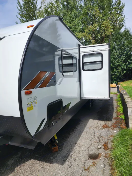 Side view of a modern white & grey travel trailer, ready for your next RV rental adventure.. Forest River Wildwood X-Lite 2022