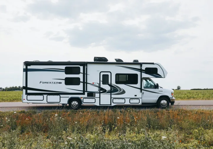 White Forester RV rental parked by a field under cloudy skies, perfect for your next road trip adventure.. Forester LE 2021