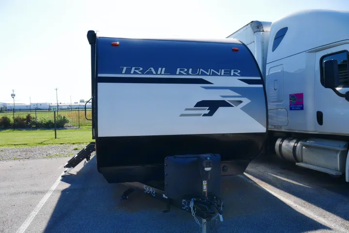 A TRAIL RUNNER travel trailer, ready for rv rental or transport, parked next to a semi-truck on a sunny day outdoors.. Heartland RVs Trailrunner 2021