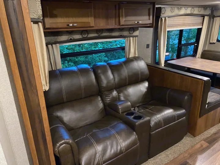 RV rental interior: cozy living area with brown leather recliners and a dinette table, offering comfort for travel.. keystone Springdale 2017