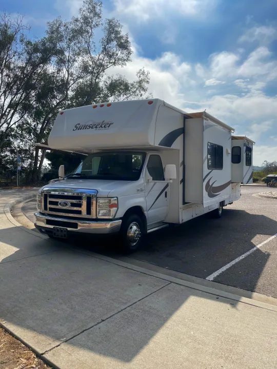 White Forest River Sunseeker Class C RV rental, fully extended, parked outdoors. Perfect for travel or camping.. Forest River Sunseeker 2009