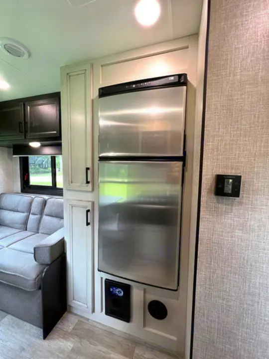 Modern RV rental interior with stainless steel fridge, cozy sofa, and white cabinetry. Your compact home on wheels awaits.. jayco Jay Flight 2022