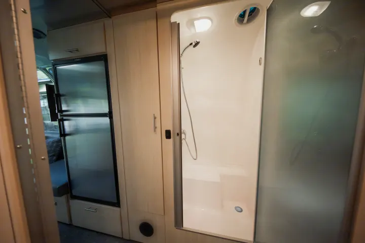 This rv rental showcases its functional interior with a Dometic refrigerator, integrated cabinetry, and a compact shower stall.. Airstream Flying Cloud 2021