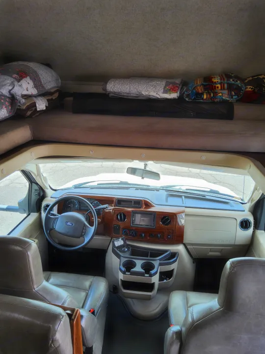 RV rental interior: The driver's cockpit with Ford steering wheel, wooden dash, and the comfy overhead sleeping bunk.. Forest River Other 2018