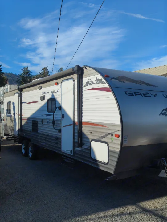 Side view of a Grey Wolf travel trailer, ideal for rv rental adventures, parked under a bright blue sky.. Forest River Cherokee Grey Wolf 2015