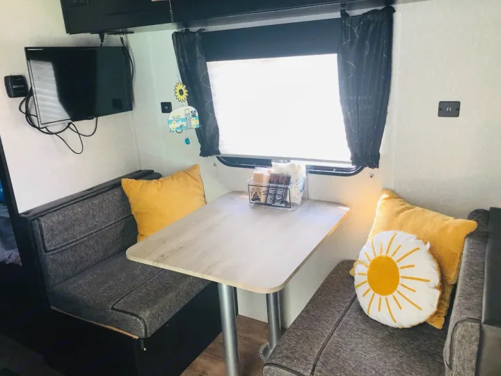 Cozy RV rental dinette: grey benches, light table, TV, window, and S'mores snacks for a comfy trip.. Forest River Cherokee Wolf Pup 2022