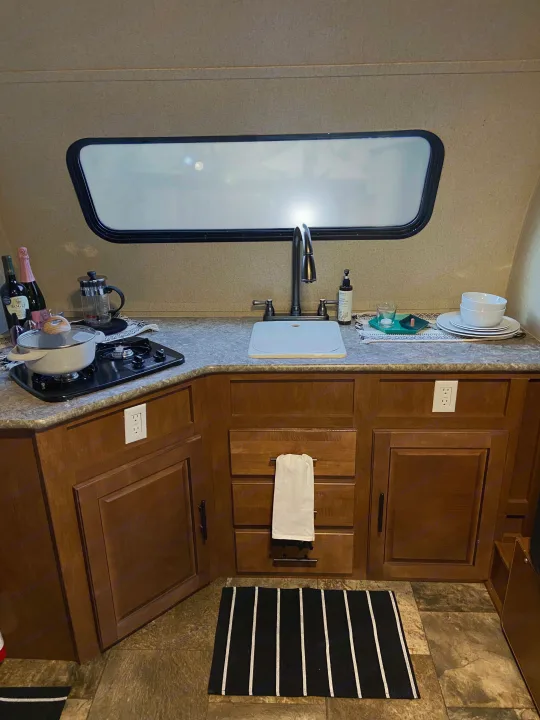 An RV rental kitchen with a sink, stove, and cabinets, set up for meals on your travels.. R-Pod Hood River Edition 2015