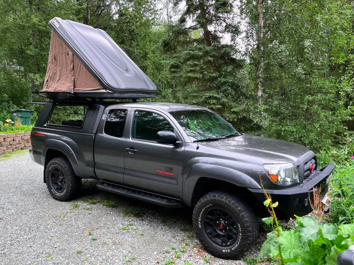 Gray Tacoma truck with deployed rooftop tent. An adventurous RV rental option for overlanding and camping trips.. Toyota Other 2010