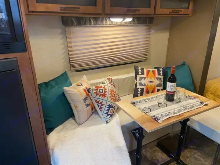 Inviting rv rental interior: cozy dinette with Southwestern pillows, wood table, wine, and window.. R-Pod Hood River Edition 2015