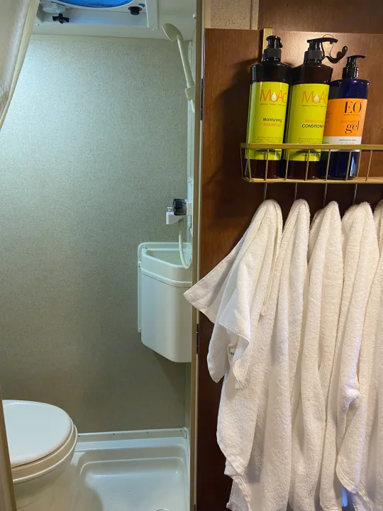 Inside an RV rental: a compact bathroom with a toilet, small sink, shower, and fresh towels next to toiletries.. R-Pod Hood River Edition 2015