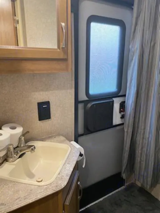 Compact **RV rental** interior: a bathroom sink, striped shower curtain, and the main access door with a window.. Forest River Coachmen Catalina SBX 2017