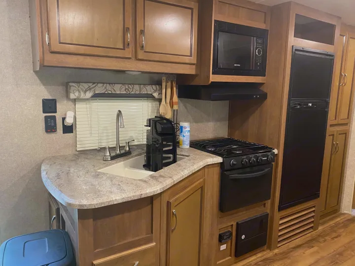 Well-equipped RV rental kitchen featuring a sink, microwave, stove, and refrigerator for all your travel cooking needs.. Forest River Coachmen Catalina SBX 2017