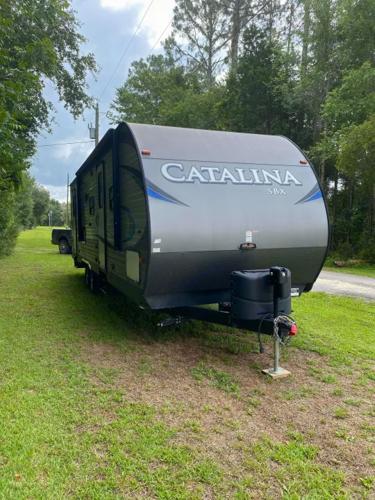 Gray Catalina SBX travel trailer parked on a grassy lot. Ideal for an RV rental getaway.. Forest River Coachmen Catalina SBX 2017
