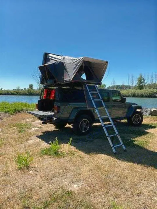 Explore with this Jeep Gladiator rv rental, featuring a rooftop tent & ladder, by the river. Ideal for camping.. Other Other 2021