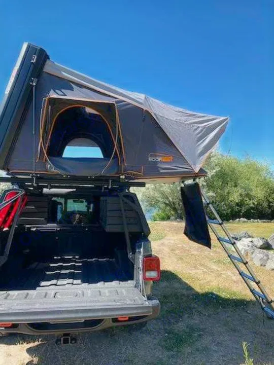 This **RV rental** features a rooftop tent mounted on a truck, set up with its ladder extended, ready for outdoor adventure and camping.. Other Other 2021