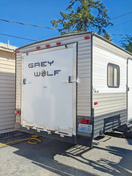 Grey Wolf travel trailer, featuring a large rear ramp door, ready for your next RV rental trip. Washington license plate visible.. Forest River Cherokee Grey Wolf 2015