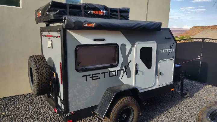 Rugged TetonX off-road teardrop camper with rooftop tent and awning. Ideal for adventure rv rental, parked on gravel.. TetonX Porter 2022