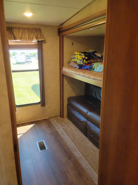 RV rental interior featuring bunk beds, a brown leather sofa, and a window with a bright outdoor view.. Crusader Crusader Fifth Wheel 2016