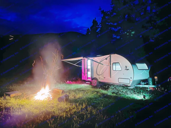 Night RV rental camping scene. Cozy campfire illuminates a small dog & travel trailer against dark hills under a deep blue sky.. R-Pod Hood River Edition 2020